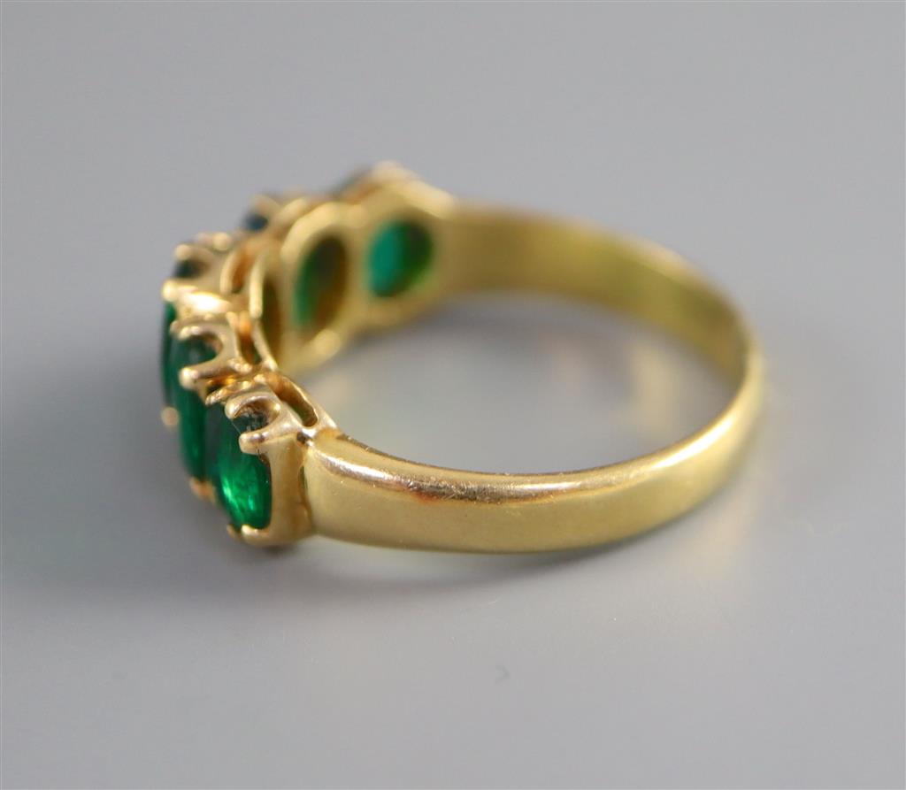 A mid to late 20th century gold and graduated five stone oval cut emerald set half hoop ring,